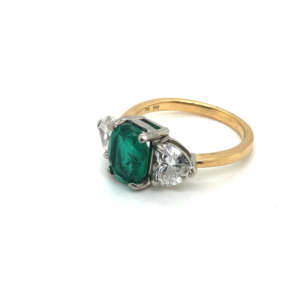 A 18ct GOLD HALLMARKED EMERALD AND DIAMOND RING. THE OVAL EMERALD FLANKED BY HEART CUT DIAMONDS. - Image 2 of 3