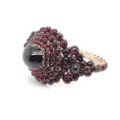 AN ANTIQUE VICTORIAN BOHEMIAN GARNET BANGLE . THE HINGED BANGLE ASSESSED AS SILVER ALLOY AND