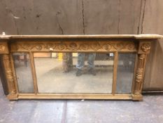 A TRIPLE PLATE MIRROR IN AN EARLY 19th C. GILT FRAME WITH COLUMNS TO EACH SIDE TOPPED BY ROSETTES,