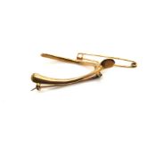 A VINTAGE WISHBONE BROOCH, UNHALLMARKED, ASSESSED AS 15ct GOLD, TOGETHER WITH A SAFETY PIN STYLE
