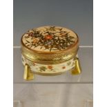 A JAPANESE SATSUMA THREE FOOTED CYLINDRICAL BOX AND COVER BY KITAMURA YAICHIRO PAINTED WITH FLOWERS.