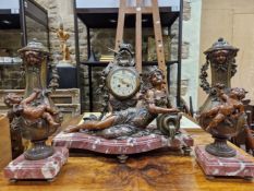 A SPELTER AND VARIEGATED RED MARBLE CLOCK GARNITURE RETAILED BY TETART OF BOULOGNE AND DESIGNED BY
