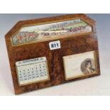 AN EASEL BACKED WALNUT CALENDAR WITH IVORINE INTERCHANGEABLE DATES BELOW A PAINTED SCENE OF A HUNT
