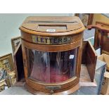 AN OAK COUNTRY HOUSE LETTER BOX, THE BOW FRONT GLAZED DOOR FLANKED BY POCKET SHELVES, DRAWER BELOW