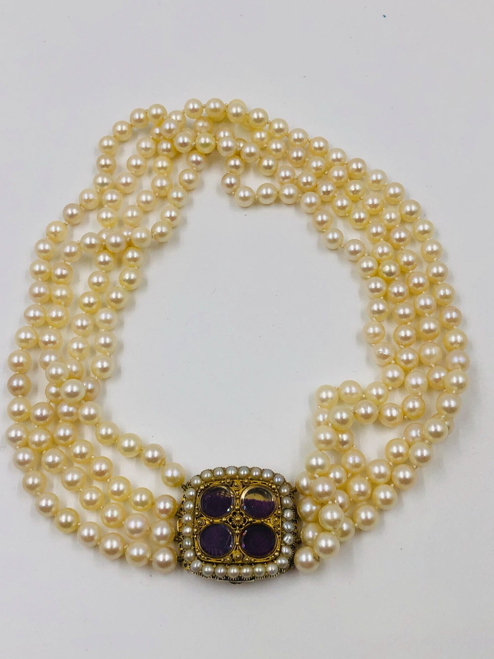 AN ANTIQUE FOUR ROW CULTURED PEARL CHOKER NECKLACE WITH GLAZED FOUR PANEL PEARL SET ORNATE CLASP.