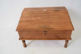 Small hardwood writing box with sloped front, opening to a storage interior raised on small turned