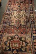 Karajeh runner carpet decorated with large medallions on a red background with geometric border