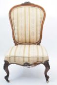 Victorian walnut framed nursing chair with striped upholstery raised on short scrolled front legs,