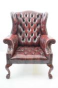 20th century red buttoned leather wingback chair raised on front cabriole legs with ball and claw