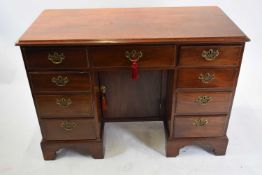 George III mahogany kneehole desk, the body with nine drawers and a central door fitted with brass