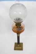 Oil lamp with white glass shade and amber glass reservoir above a Corinthian column, the lamp 50cm