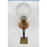 Oil lamp with white glass shade and amber glass reservoir above a Corinthian column, the lamp 50cm