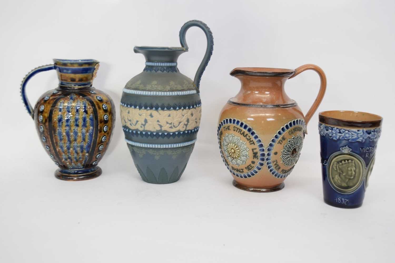 Group of three Doulton ware jugs including one with mask spout and further Doulton commemorative