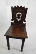 Victorian oak Gothic carved hall chair with pierced shield decorated back, raised on bobbin turned