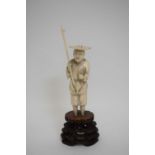 Ivory okimono figure of a fisherman, Meiji period, on carved wooden stand, 14cm high