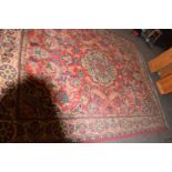 20TH CENTURY WOOL FLOOR RUG DECORATED WITH LARGE CENTRAL PANEL ON A PRINCIPALLY RED BACKGROUND,