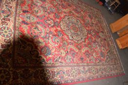 20TH CENTURY WOOL FLOOR RUG DECORATED WITH LARGE CENTRAL PANEL ON A PRINCIPALLY RED BACKGROUND,