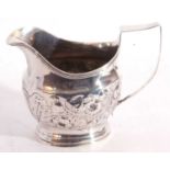 Georgian silver cream jug of helmet shape, later embossed with scrolls of flowers and foliage, the
