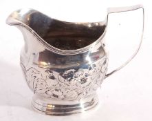 Georgian silver cream jug of helmet shape, later embossed with scrolls of flowers and foliage, the