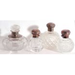 Group of four cut glass table scent bottles to include a Victorian large bottle with silver neck and