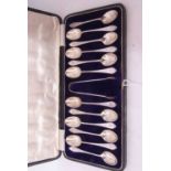 Cased set of 12 George V dog-nose and rat-tail tea spoons, each initialled with 'R' in script to the