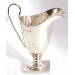 Edwardian silver cream jug of plain helmet shape raised from a square pedestal foot, 10.5cm tall,