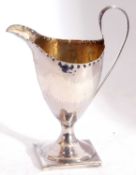 George III silver pedestal cream jug of helmet shape, having a punched border and with loop