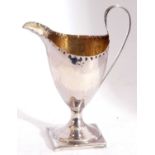 George III silver pedestal cream jug of helmet shape, having a punched border and with loop