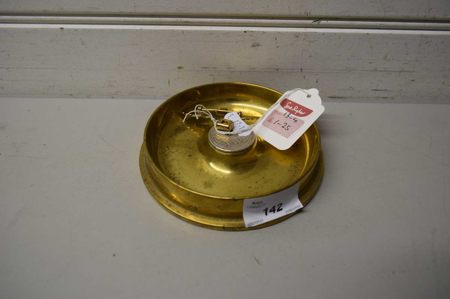 BRASS ASHTRAY FORMED FROM THE END OF A SHELL CASE TOGETHER WITH A FURTHER BASE METAL BROOCH