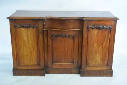 Victorian mahogany sideboard with central serpentine drawer and three panelled doors raised on a