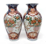 Pair of Japanese porcelain vases with Imari design and central cartouche of flowers in a vase,