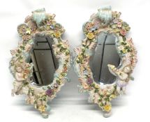 Pair of ornate late 19th century mirrors within ceramic holders, moulded with flowers and cherubs,