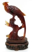 Amber coloured glass model of a pheasant on shaped wooden stand