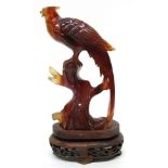 Amber coloured glass model of a pheasant on shaped wooden stand