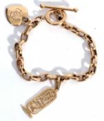Modern 585 stamped oval link bracelet suspending a hieroglyphic pendant and a heart pendant,
