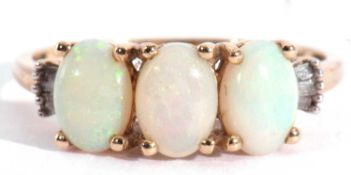 Modern 9ct gold white opal three stone ring, featuring three oval cabochon opals, the shoulders each