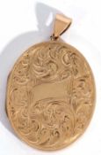9ct gold large oval shaped hinged locket, the front elaborately engraved and chased with scrolls