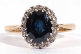 Sapphire and diamond cluster ring, the oval faceted dark sapphire 9.26mm x 7.52mm x 3.24mm, within a