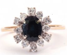 Modern sapphire and diamond cluster ring, the oval faceted dark sapphire within a small diamond