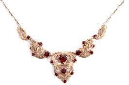 9ct gold and garnet set necklace, the open work leaf design set with graduated round faceted