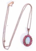 Opal and ruby pendant, the oval cabochon opal in cut down setting within a small ruby stone surround