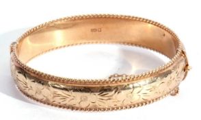 9ct gold hollow hinged bracelet, chased and engraved all over with a floral design, between rope