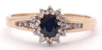 9ct gold sapphire and diamond cluster ring, the oval cut dark sapphire multi-claw set and raised