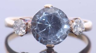 18ct gold blue topaz and diamond ring, the round cut topaz cardinal set and flanked by two old cut