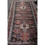 Middle Eastern wool floor rug decorated with large central panel with geometric design surrounded by