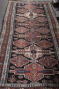 Middle Eastern wool floor rug decorated with large central panel with geometric design surrounded by