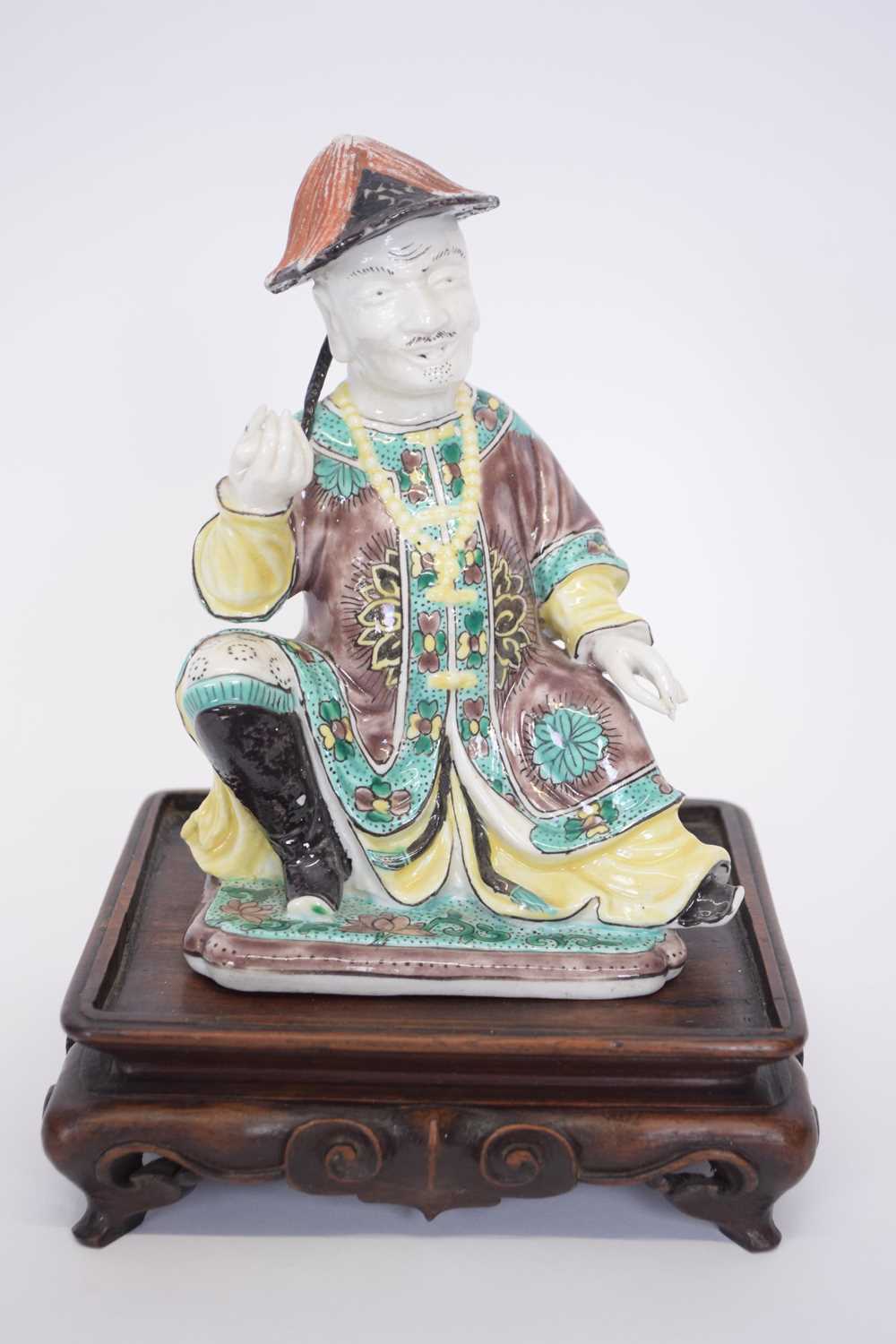 Chinese ceramic figure of a chinaman on wooden base with predominantly famille vert decoration on