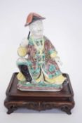 Chinese ceramic figure of a chinaman on wooden base with predominantly famille vert decoration on