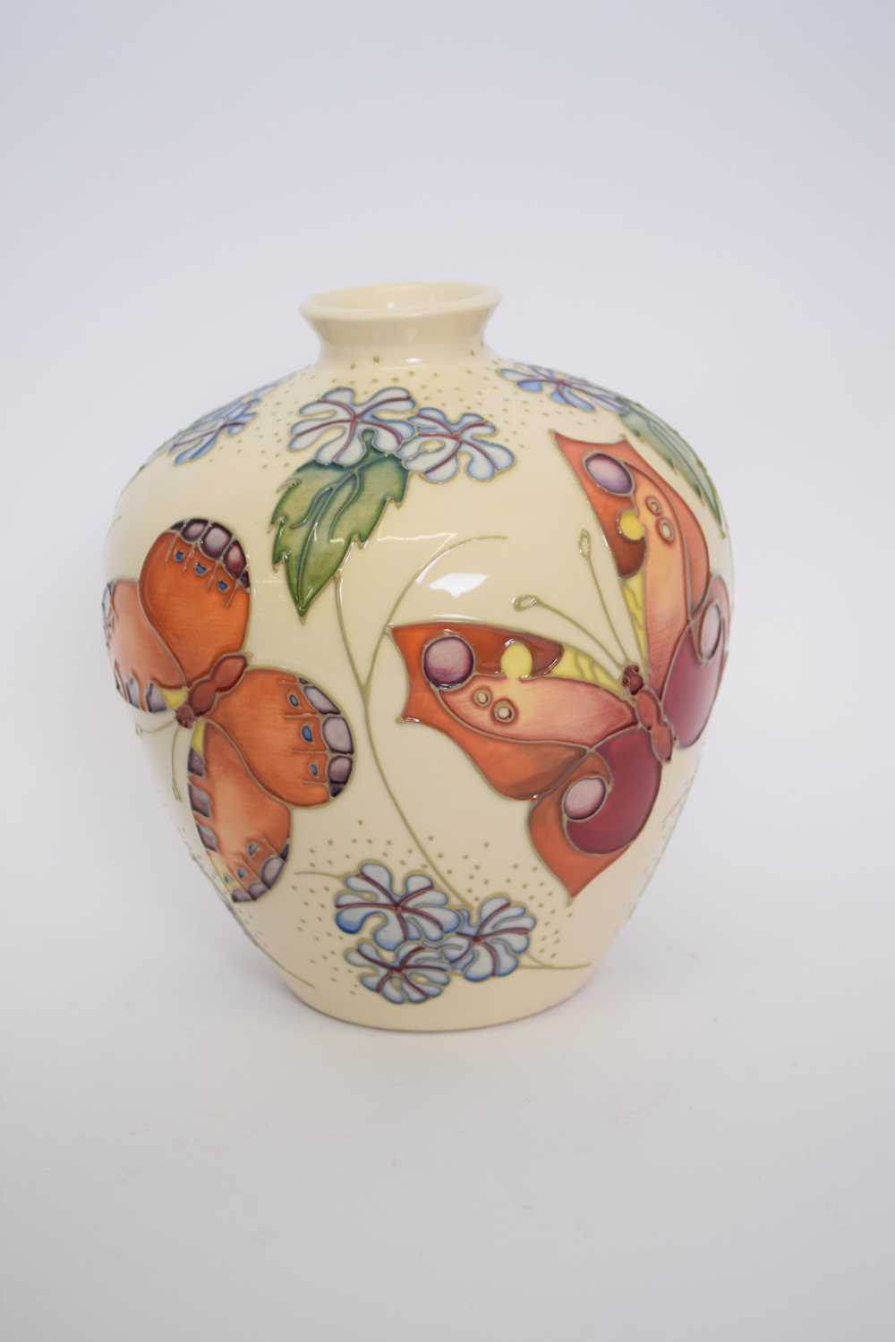 Moorcroft vase with tube lined design of butterflies on a pale beige ground