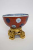 Oriental porcelain bowl decorated with Mons on a red ground mounted on ormolu mount, 18cm diam (